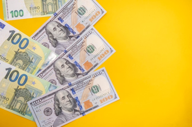 Foto 100-dollar- und euro-banknoten auf gelbem hintergrund. platz für textkopierraum. banner mit währung. börse. wirtschaftskrise. platz für text. geschäftsplan