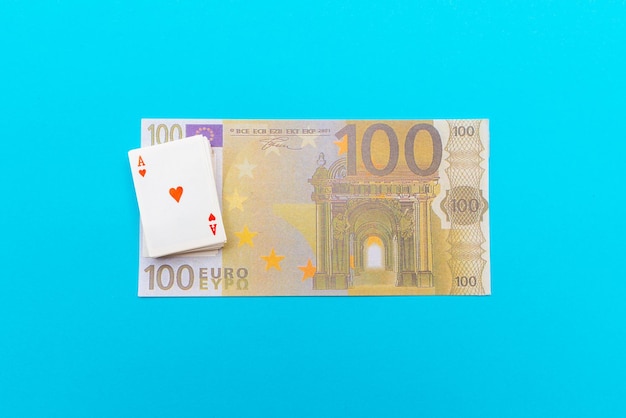100 Euro With One Note und kleine Spielzeugkarten liegen auf dem blauen Hintergrund der Banknoten