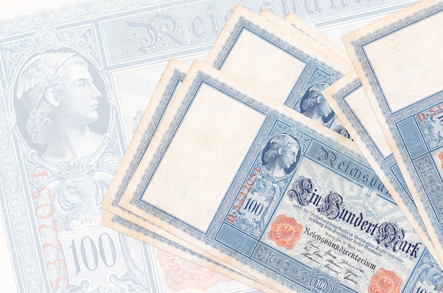 100 Reichsmarkscheine liegen gestapelt an der Wand einer großen halbtransparenten Banknote. Abstrakte Darstellung der Landeswährung. Unternehmenskonzept