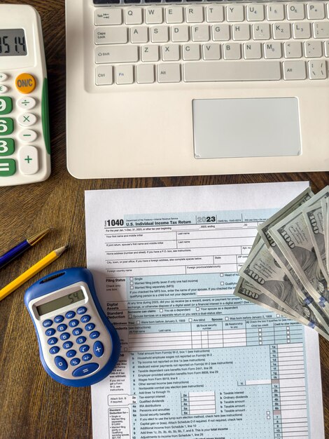 Foto 1040 formularios de impuestos con dólares de calculadora y una pluma portátil en el escritorio de la oficina