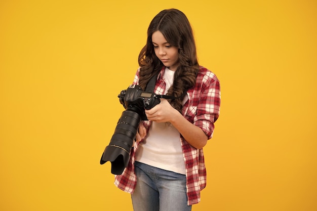 Foto 12 13 adolescente de 14 anos segurando câmera digital ou dslr sobre fundo amarelo