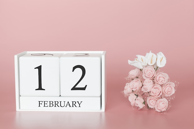 12 de febrero. Día 12 del mes. Haga calendarios el cubo en fondo rosado moderno, el concepto de negocio y un acontecimiento importante.