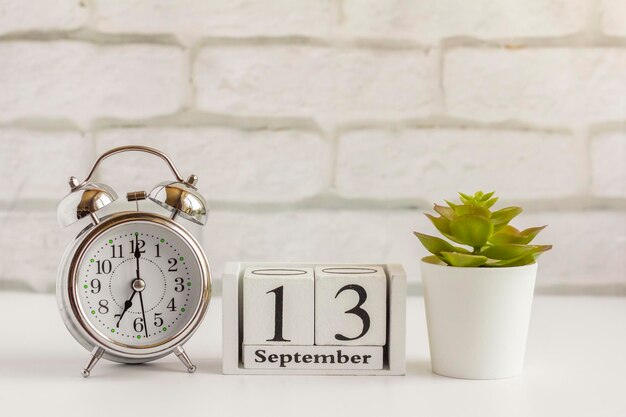 Foto 13 de setembro em um calendário de madeira ao lado do despertadordia de setembro espaço vazio para textocalendar para setembro em um fundo claro