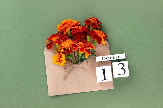 13 de octubre Ramo de flor de naranja en sobre artesanal y fecha de calendario sobre fondo verde Concepto mínimo Hola plantilla de otoño para su tarjeta de felicitación de diseño