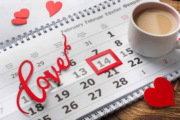 14 de fevereiro Calendário. Conceito do dia de Valentim, corações vermelhos, o amor da palavra e uma xícara de café.