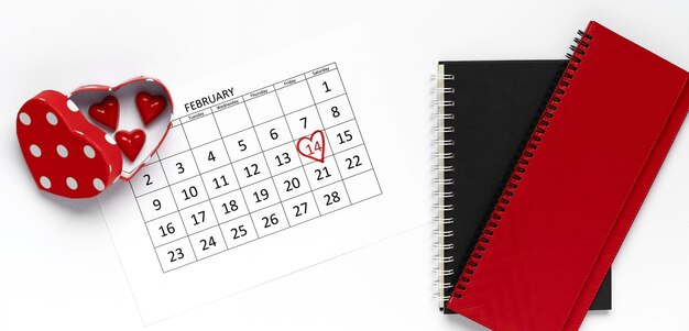 14. Februar Kalender mit Süßigkeiten Herzform und Notizbüchern. Flache Lage, Draufsicht. Valentinstag Konzept