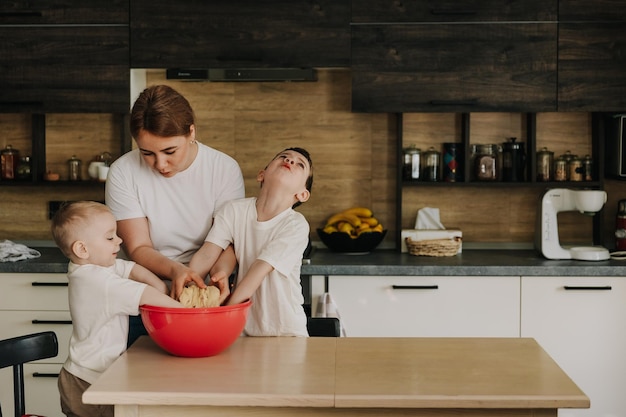 18112018 Vinnitsa Ucrânia mãe com filhos amassa a massa para deliciosos doces que eles preparam na cozinha em casa