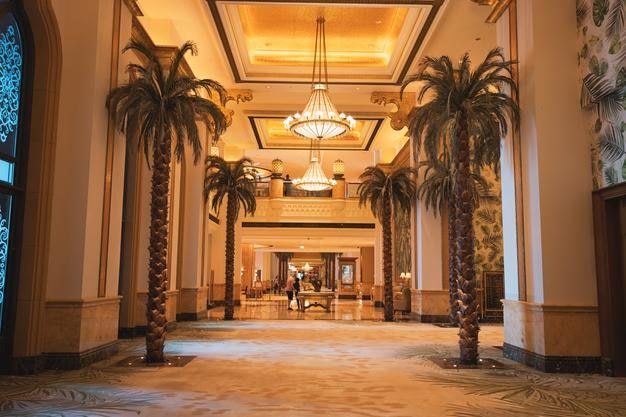 19 de enero de 2025 Emirates Palace Hotel Abu Dhabi UAE Palmeras decorando un largo pasillo con elegantes candelabros y alfombras en un lujoso hotel