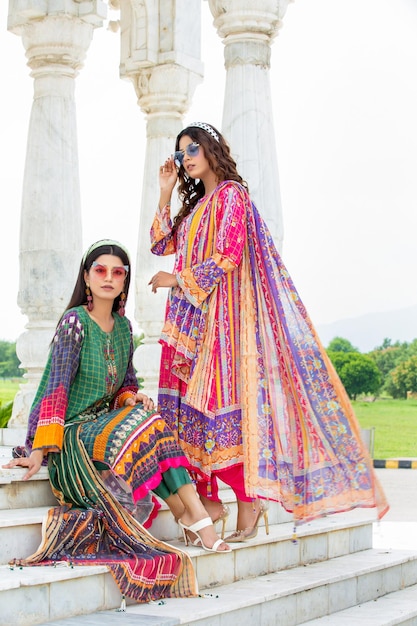 2 chicas atractivas posando en las escaleras del jardín con vestidos tradicionales Desi para una sesión de fotos al aire libre
