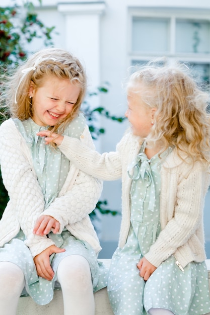 2 kleine Mädchen mit hellen Haaren lachen Schwesternliebe Die Wettermädchen lieben sich sehr Nur