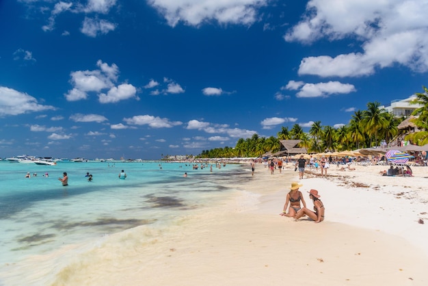 2 sexy Mädchen sitzen im brasilianischen String-Bikini an einem weißen Sandstrand in der türkisfarbenen Karibik Isla Mujeres Insel Karibik Cancun Yucatan Mexiko