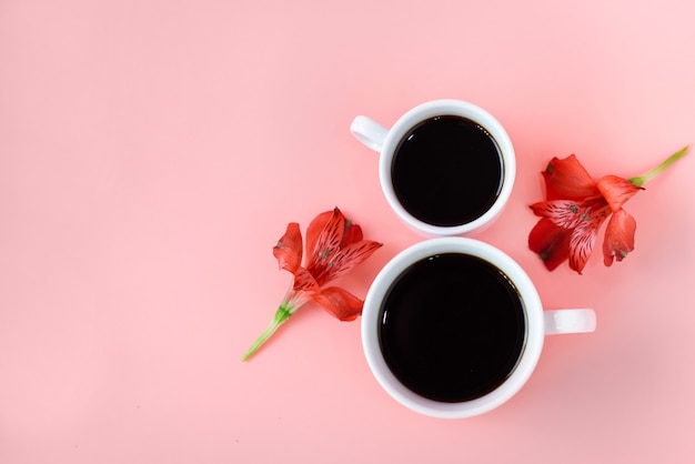 2 xícaras de café com flores sobre fundo rosa.