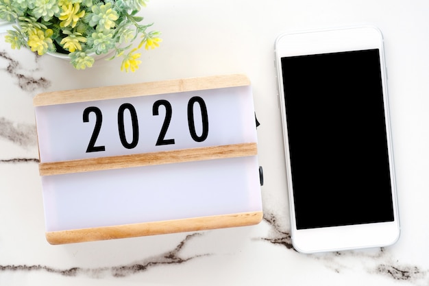 2018 na caixa de madeira e telefone com tela em branco sobre fundo de mesa de mármore branco
