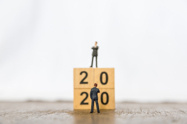 2020 ano novo e planejamento de negócios. feche acima da figura em miniatura de dois empresário em pé na frente da pilha de blocos de madeira número