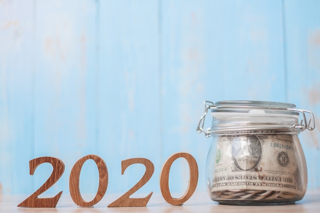 2020 año nuevo con dinero tarro de cristal y número de madera.