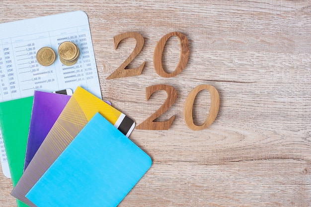 2020 feliz año nuevo con banco de libros y monedas en mesa de madera