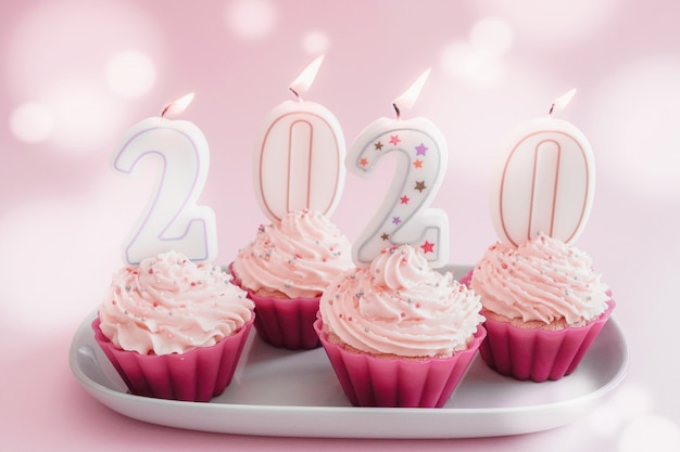2020 velas em cupcakes com cobertura de creme de chantilly usando copos reutilizáveis de silicone rosa
