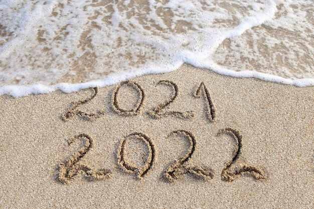 2021, 2022 Jahre geschrieben am Sandstrand Meer. Welle wäscht 2021 weg.