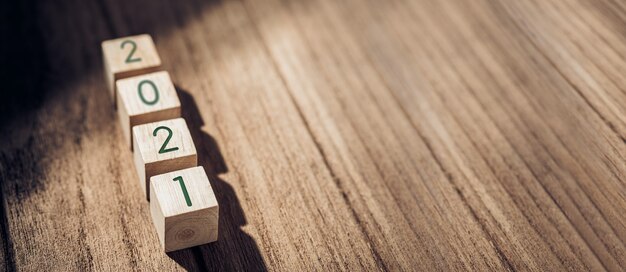 2021 bloque de madera sobre mesa de madera y muro de hormigón con luz solar desde la ventana