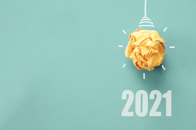 Foto 2021 y bombilla de luz de papel amarillo sobre superficie azul