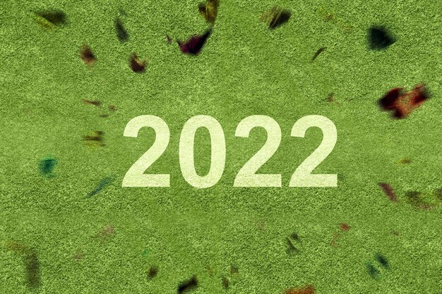 2022 auf dem grünen Gras mit Konfettihintergrund. Frohes neues Jahr 2022