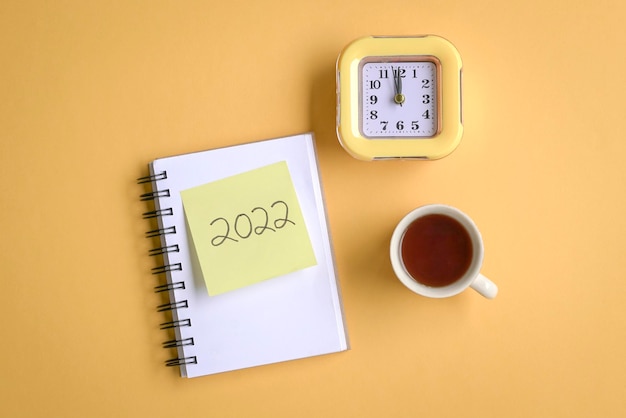 2022 en bloc de notas con reloj y taza de café.