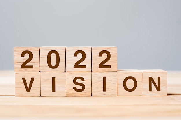 2022 bloque de cubo VISION en el fondo de la tabla. Conceptos de resolución, plan, revisión, meta, inicio y vacaciones de Año Nuevo