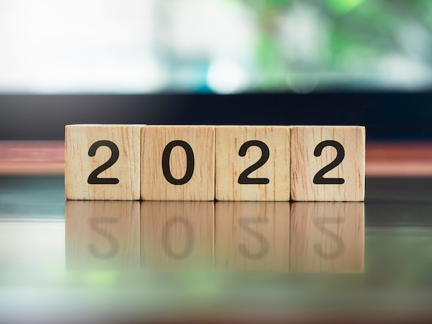 2022, concepto de año nuevo, números en bloques de cubos de madera en el escritorio de madera marrón y fondo verde de la naturaleza.