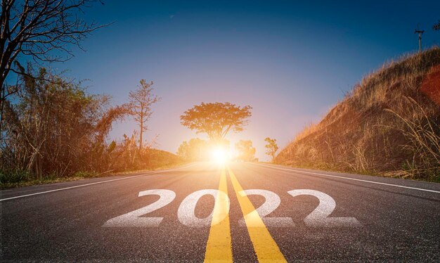 2022 escrito en la carretera. Carretera de asfalto vacía y fondo de cielo hermoso amanecer. Concepto de meta y desafío para la visión del año nuevo 2022.