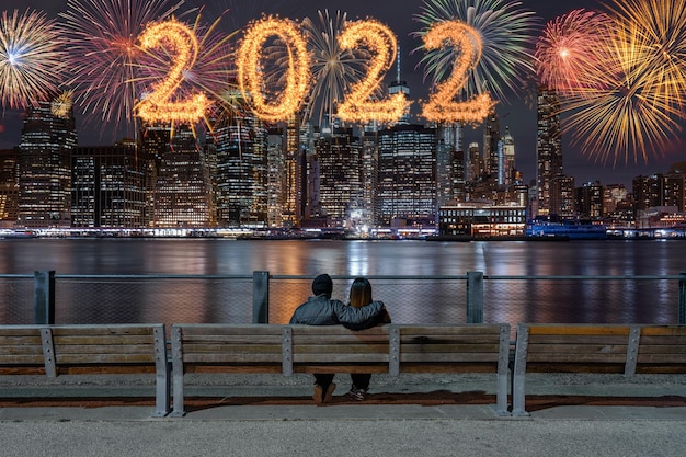 2022 escrito com sparkle fireworks com várias cores de fogos de artifício nas costas do casal sentado