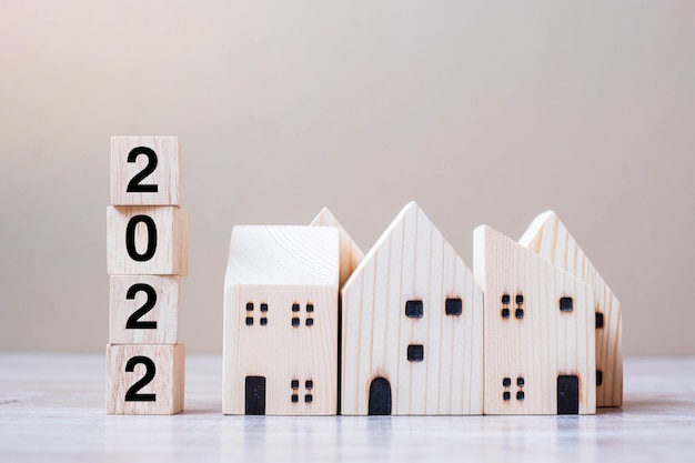 2022 feliz ano novo com modelo de casa no fundo de madeira da mesa. Conceitos de banco, imobiliário, investimento, financeiro, poupança e resolução de ano novo