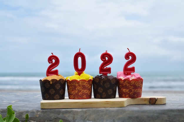 2022 Feliz año nuevo con cupcakes y velas en la playa