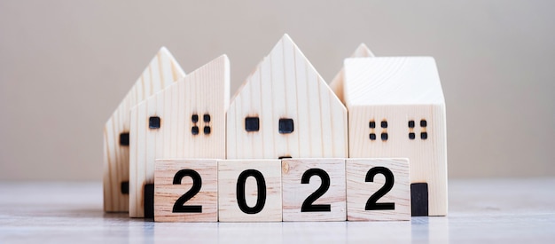 2022 Feliz año nuevo con modelo de casa sobre fondo de madera de mesa. Conceptos bancarios, inmobiliarios, de inversión, financieros, de ahorro y de resolución de año nuevo