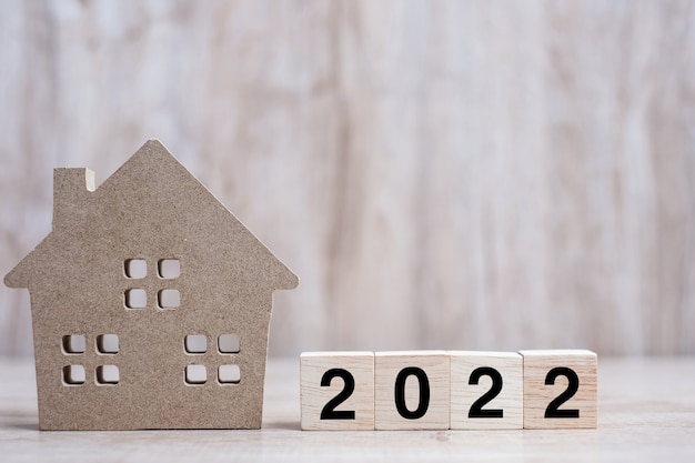 2022 Feliz año nuevo con modelo de casa sobre fondo de madera de mesa. Conceptos bancarios, inmobiliarios, de inversión, financieros, de ahorro y de resolución de año nuevo