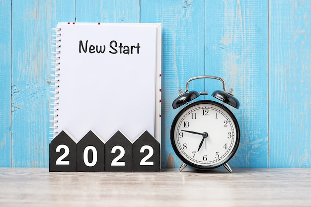 2022 Feliz año nuevo con nuevo comienzo, reloj despertador retro negro y número de madera.Resolución, metas, plan, acción y concepto de misión