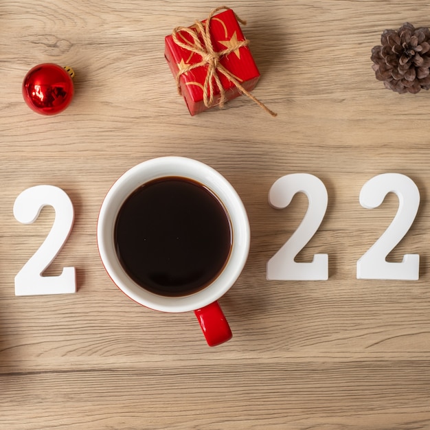 2022 Feliz año nuevo con taza de café y decoración navideña sobre fondo de mesa de madera. Nuevo comienzo, resolución, cuenta atrás, metas, plan, acción y concepto de misión