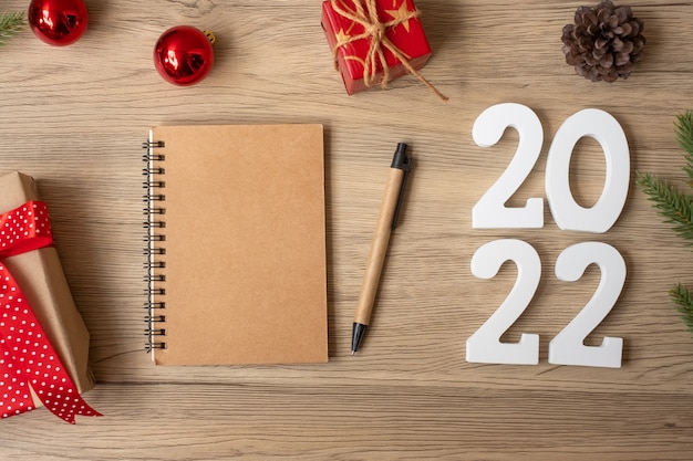 2022 Reveillon com caderno, presente de Natal e caneta na mesa de madeira. Natal, feliz ano novo, objetivos, resolução, lista de tarefas, início, conceito de estratégia e plano