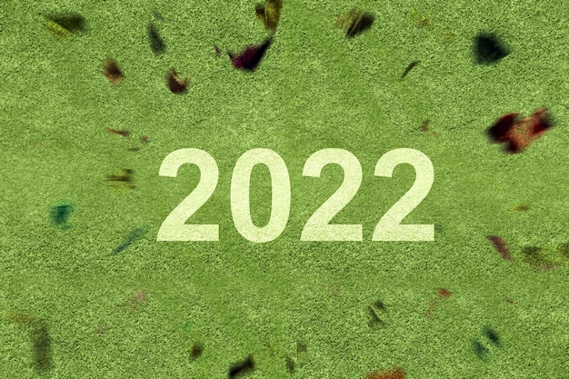 2022 sobre la hierba verde con un fondo de confeti. Feliz año nuevo 2022