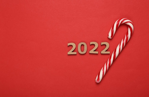 2022 und gestreifte Zuckerstange auf rotem Hintergrund Weihnachtsneujahrskomposition