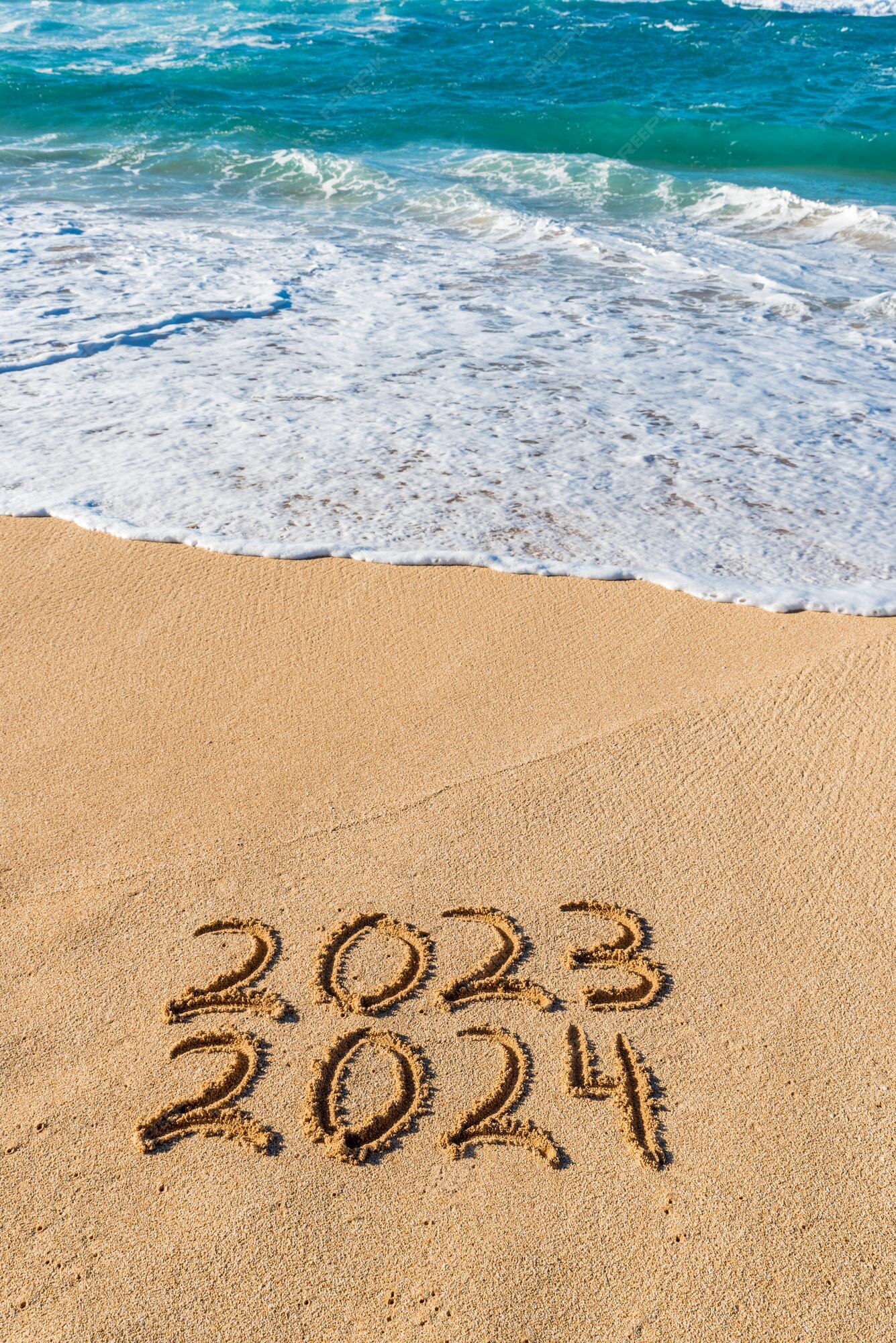 2023 2024 escrito en la arena con olas lavando el concepto de año nuevo