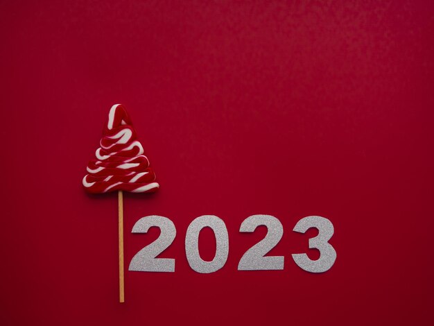 2023 y caramelo rojo blanco en forma de árbol de Navidad sobre fondo rojo