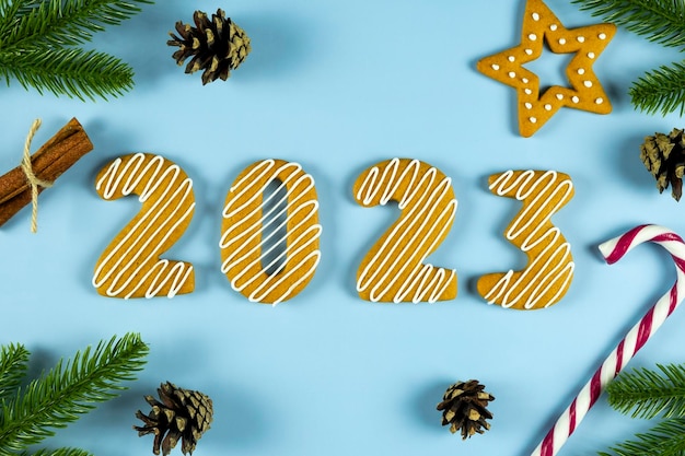 2023 Cookie-Nummer aus Lebkuchenplätzchen mit weißem Zuckerguss mit Tannenzweigen, Kegelstern und Süßigkeiten auf blauem Hintergrund Frohe Weihnachten und ein gutes neues Jahr