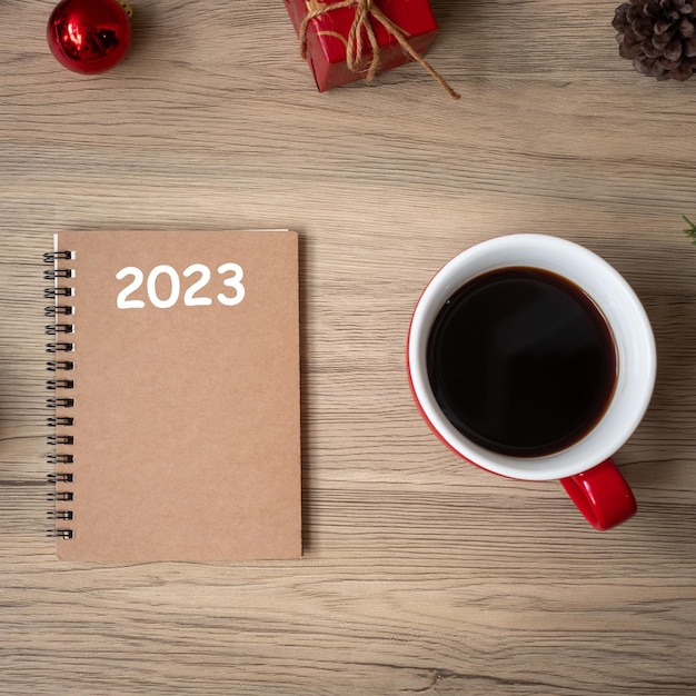 2023 cuaderno taza de café negro y regalo de Navidad en la mesa de madera Vista superior y espacio de copia Navidad Feliz Año Nuevo Resolución de objetivos Lista de tareas Concepto de estrategia y plan