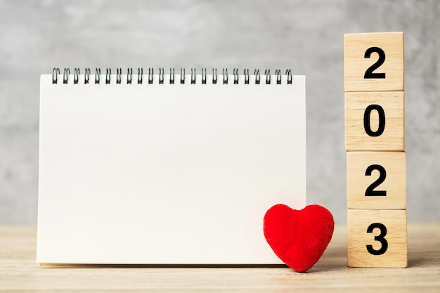 2023 cubos con forma de corazón rojo y cuaderno vacío en la mesa para su texto Resolución de Año Nuevo Plan de objetivos salud Amor y concepto de feliz día de San Valentín