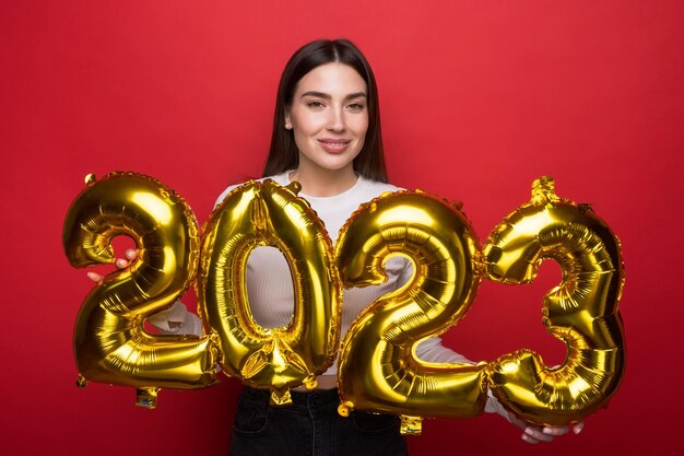 2023 es el año del conejo según el calendario oriental Una joven sonriente sostiene globos en forma de 2023 sobre un fondo rojo