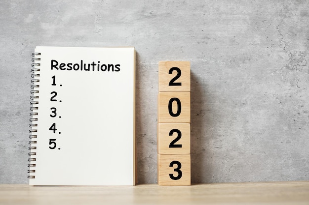 2023 Frohes Neues Jahr mit Auflösungsnotizbuch und hölzernem Zahlencountdown Zielplan Aktion und Missionskonzept