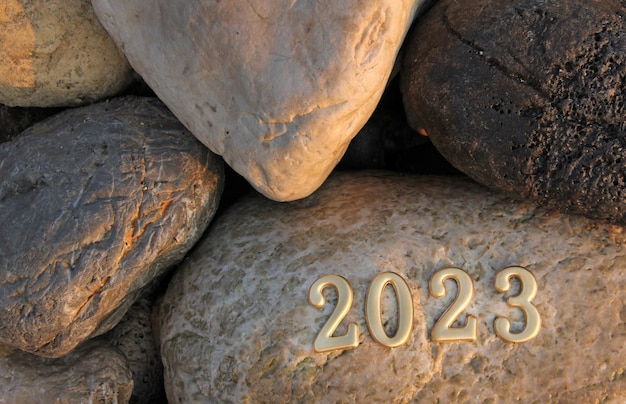 2023 goldene Farbnummer auf Stein mit verschwommenem Hintergrund Neujahrskonzept