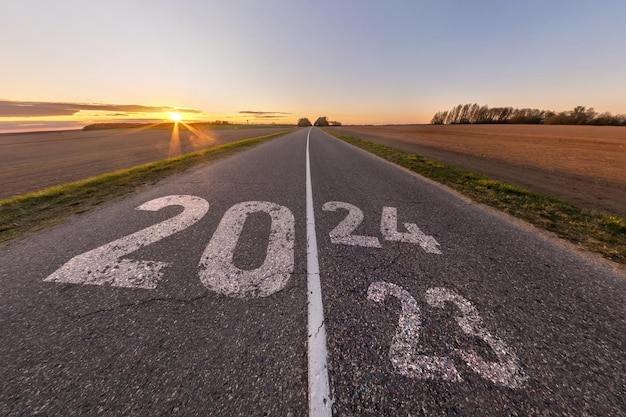 2023 sinal 2024 e começar em estrada de asfalto rodovia com nascer ou pôr do sol céu de fundo conceito de destino no futuro liberdade de trabalho começar a correr planejamento desafio alvo ano novo