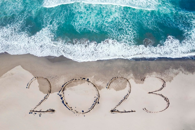 2023 Zahlen auf den Sand der Küste geschrieben