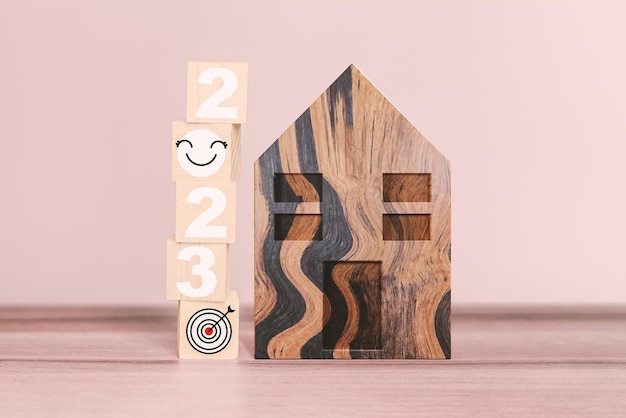 2023 Zahlen und Smiley-Symbol mit dem Ziel, ein eigenes Zuhause auf einem Holzwürfel zu haben